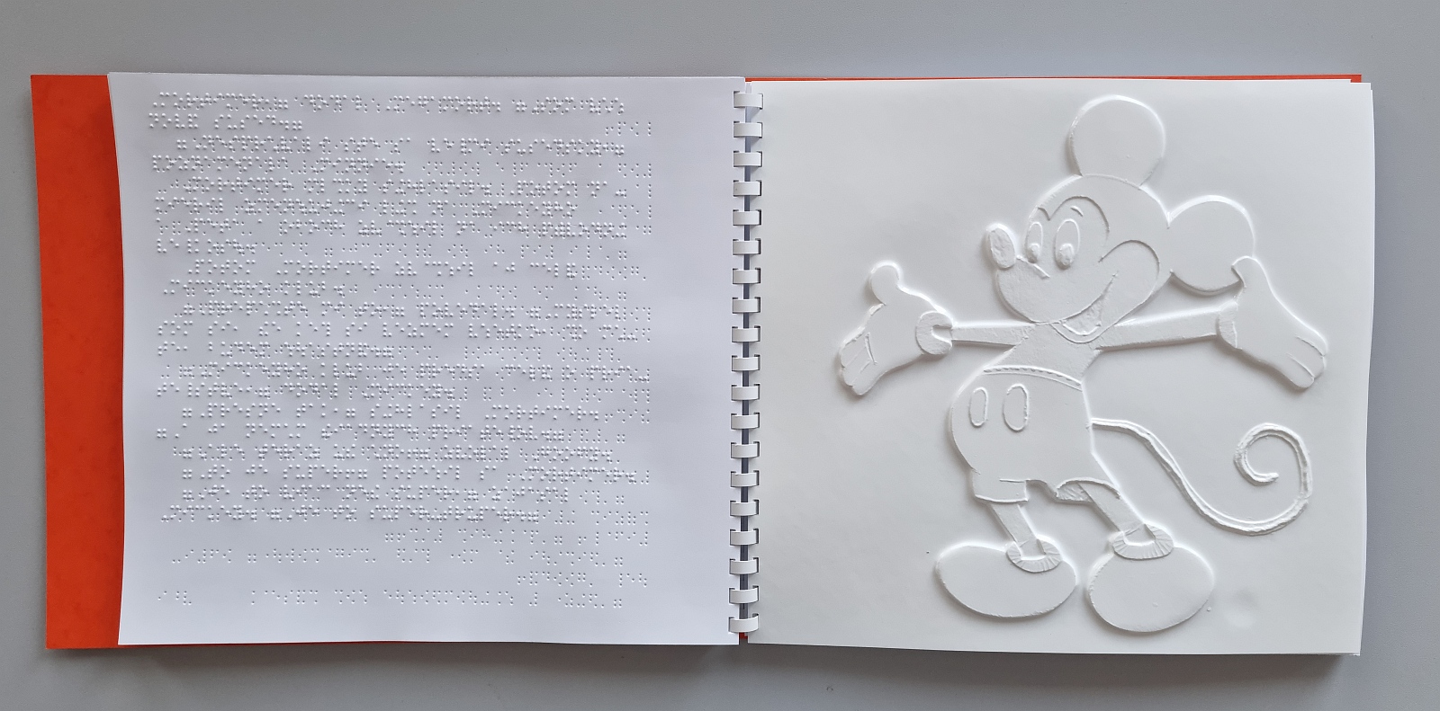 Na obrázku je fotografia reliéfnej ilustrácie knižky, obrázok Mickeyho.
